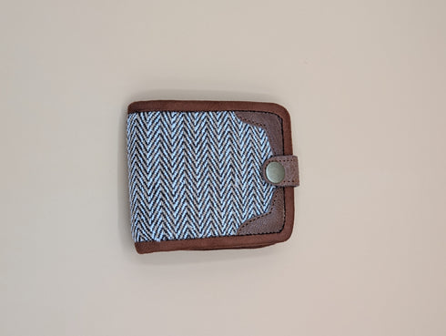 Small pouch with blue patterned fabric and brown leather trim on a beige background